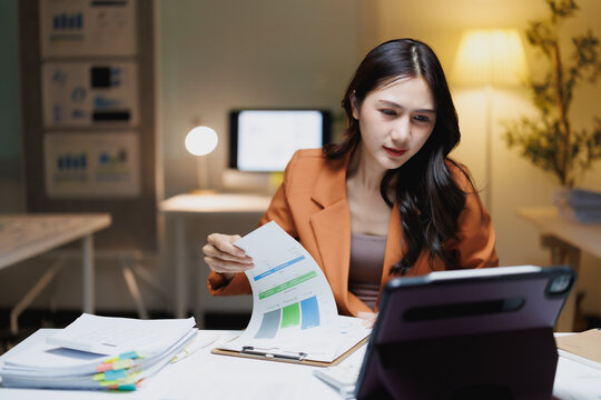 Asian businesswoman analyzing financial report data in office