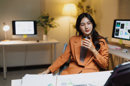 Asian businesswoman working late drinking coffee at office
