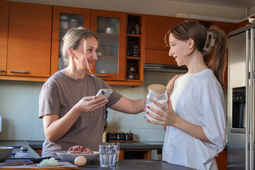 Mother and daughter searching for a recipe on a smartphone. A warm and authentic family cooking together at home, showing two generations preparing traditional dumplings