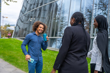 Diverse colleagues having coffee break outdoors by modern architecture
