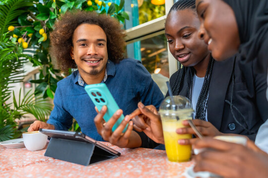 Diverse group of friends discussing using smartphone at cafe