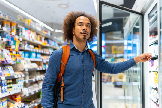 Man shopping for groceries at supermarket refrigerator section - Powered by Adobe
