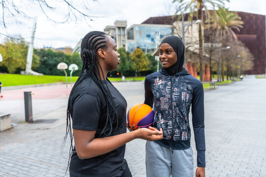 Diverse young women talking and holding basketball - Powered by Adobe