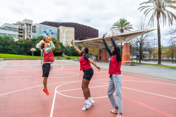 Diverse friends playing basketball together on urban court