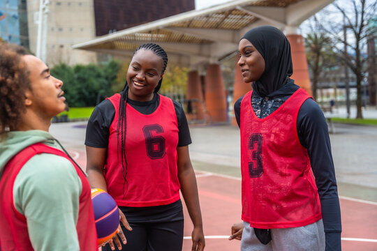 Diverse youth basketball team talking on outdoor court