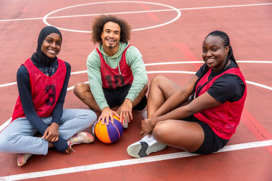 Diverse young friends smiling on outdoor basketball court