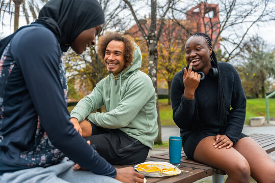 Diverse african friends laughing and eating outdoors in park