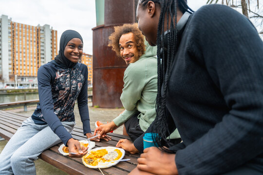 Diverse friends sharing a meal outdoors in urban setting - Powered by Adobe