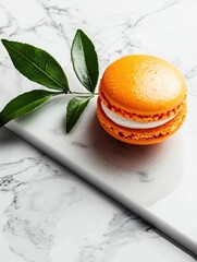 Single orange macaron on a white marble surface. the macaron is round and has a golden-brown color. it is stacked on top of each other, with the top layer being slightly darker than the bottom layer.