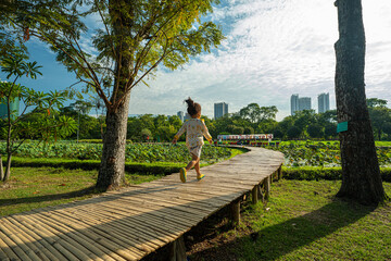 Adorable little kindergarten girl enjoy free play run on wooden pathway city park building