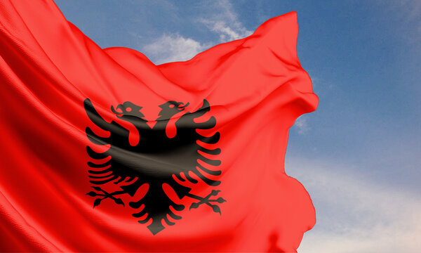 The Albania flag waving in the blue sky on a flagpole, celebrating Independence Day with the national emblem on flowing fabric.