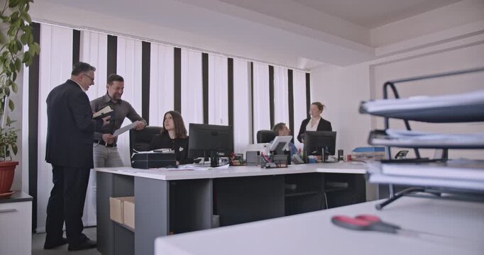 Business colleagues discuss documents in an office environment. Teamwork and collaboration are evident as they work together on a project.