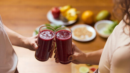 Two glasses of berry smoothie clinking together over wooden table with fresh ingredients. Concept of beverage branding, wellness campaign visuals, smoothie lifestyle posts, recipe promotion.