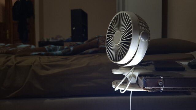 Portable mini fan sitting on a desk, dramatically illuminated from below. Focus on technology, cooling, and modern personal device accessories