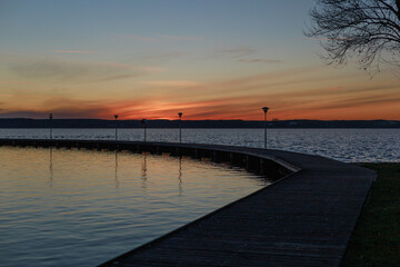 Pier curve into sunset lake.Curved pier leads into a lake under sunset colors. Concept of journey metaphor, poster design, emotional storytelling, and inspirational visual