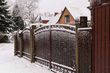 Snow covered wooden gate. Wrought iron garden gate covered with fresh snow in a residential yard. Concept of winter architecture detail, design background, and seasonal visual.