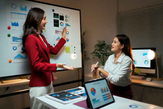 Businesswomen analyzing data and presenting project late at night