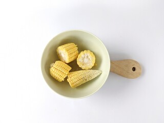 Pieces of corn sitting in a bowl on a white background