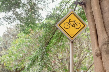 Bicycle road sign in the park. Bicycle sign with shady trees in the background.