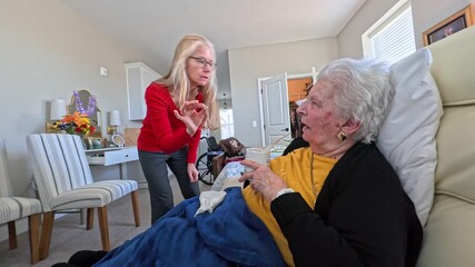 A touching moment as an elderly woman talks with her daughter during a visit at a nursing home, sharing smiles and conversation.