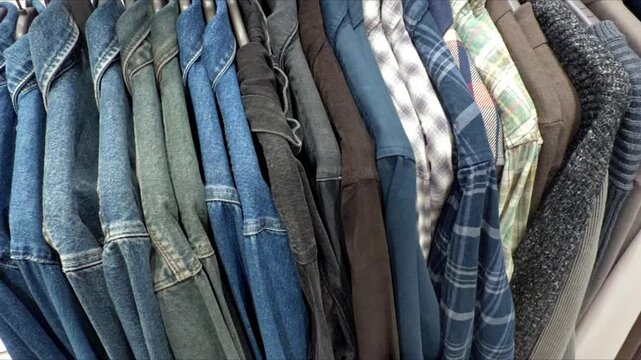 Shirts hanging on hangers in a clothing store, side view.
