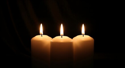 Three white candles burning brightly in a dark, tranquil setting