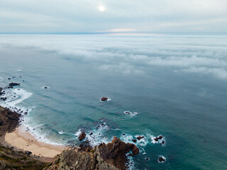 Aerial View of Secluded Beach and Rocky Shoreline Beneath Fog-Covered Atlantic Ocean at Cabo da Roca, Sintra, Portugal