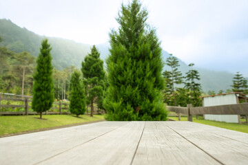 Wooden table in focus with tall green trees in a farm landscape