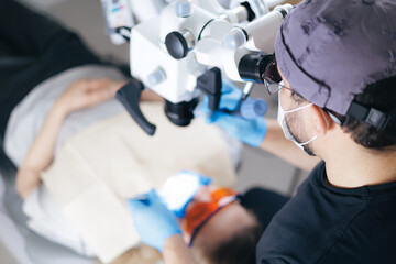 Male surgeon performing eye surgery using microscope in operating room, top view
