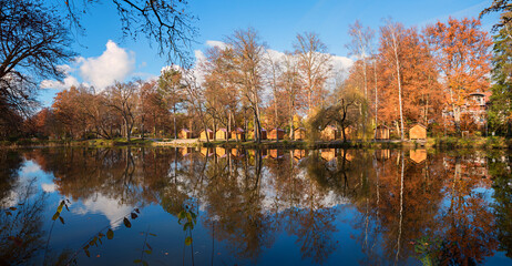 row of wooden market huts, autumnal trees. both reflecting in the lake. spa garden Bad Aibling