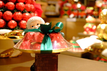 Christmas chocolates with Santa Claus figures. Gift chocolates with red packaging, green ribbons, and yellow balls. Happy New Year. Welcome 2026. Merry Christmas.