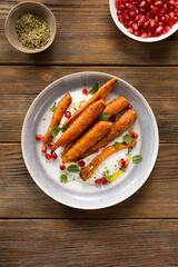Roasted baby carrots on plate top view wooden surface