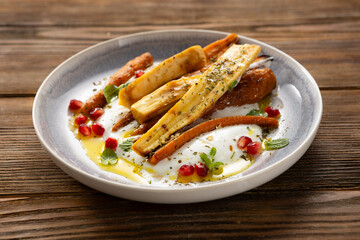 Close up of roasted carrot and parsnip yogurt  wooden surface