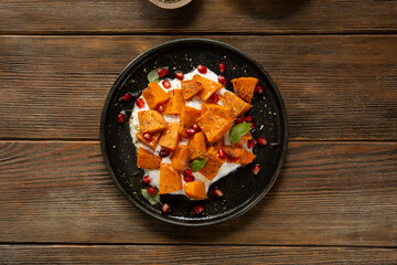 Top view of roasted pumpkin slice on black plate wooden surface