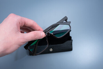 Hand Holding Glasses Above Black Case