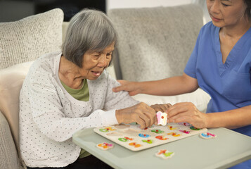Nurse in Blue Uniform Assists Elderly Woman with Number Puzzle Game in Dementia Care.