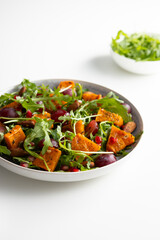 Fresh salad with pumpkin and grapes on plate  close up