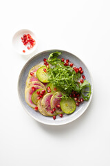 Fresh salad with sliced watermelon radish on plate  light surface