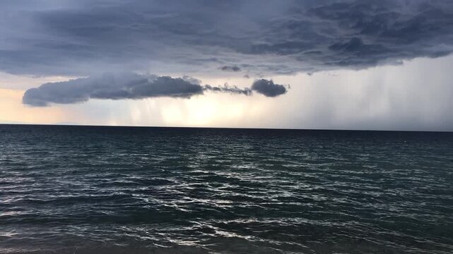 Dramatic storm clouds gather over the ocean, showcasing a captivating transition in lighting and atmosphere as the camera pans across the seascape, revealing nature's power
