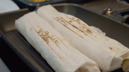 Lavash kebabs are cooked on a grill pan, showcasing the step-by-step process of browning and preparing this tasty dish in a home kitchen setting.