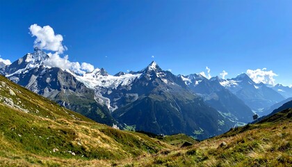 Fototapeta premium Sweeping mountain vista with grassy slopes, snow-capped peaks, and vibrant blue sky on a sunny day