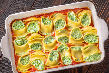 Golden baked lumaconi filled with ricotta and spinach resting in rich tomato sauce