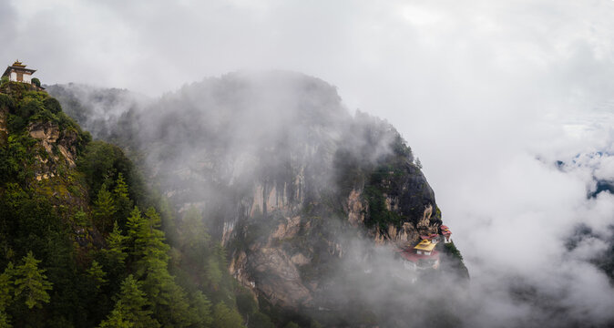 Aerial view of the Taktsang Palphug Monastery, also known as Tigers Nest, clinging to the cliffside amidst swirling clouds, Paro, Bhutan.