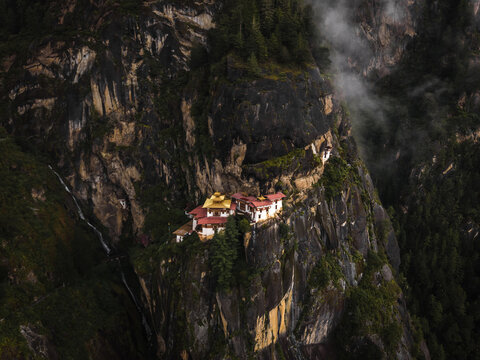 Aerial view of the monastery clinging to the cliffside, a testament to faith against the rugged terrain of Tiger's Nest, Paro, Bhutan.