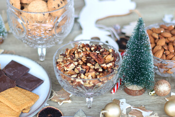 Various Christmas decorations, cookies, chocolate and nuts on wooden background. Selective focus.