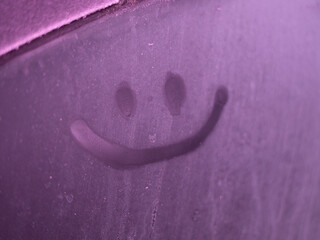 A playful smiley face drawn on a purple foggy surface, blending cold winter texture with a vivid, colorful tone that enhances the cheerful and uplifting mood of the simple expression.