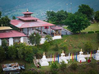 Aerial view of the Sangchhen Dorji Lhuendrup Lhakhang Nunnery with its red roofs and white stupas cascading down the hillside, Walakha, Punakha, Bhutan.