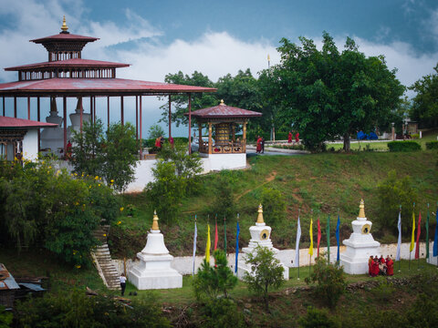 Aerial view of the Sangchhen Dorji Lhuendrup Lhakhang Nunnery with its golden spires, prayer wheels, and vibrant prayer flags amid the lush green landscape, Walakha, Punakha, Bhutan.