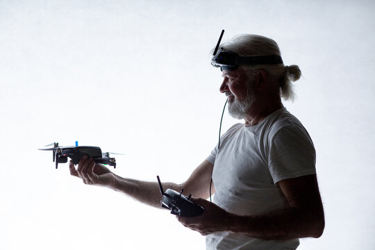 Silhouetted elderly man put a drone in his hand on studio background, modern hobby and technology, human tamed technologies