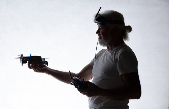 Silhouetted elderly man put a drone in his hand on studio background, modern hobby and technology, human tamed technologies